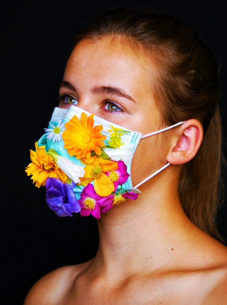 Vrouw met mondkapje dat versierd is met kleurige bloemen
