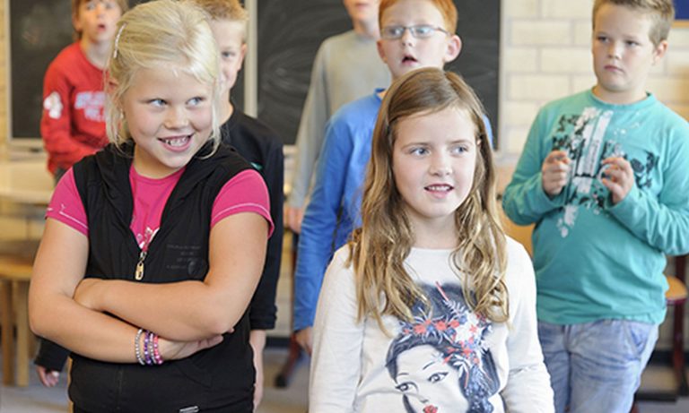 Groepje leerlingen staat in een bevroren houding tijdens dramales