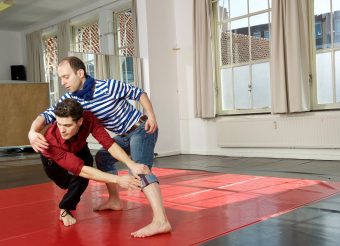 Twee dansers van De Stilte dansen op een rode vloer