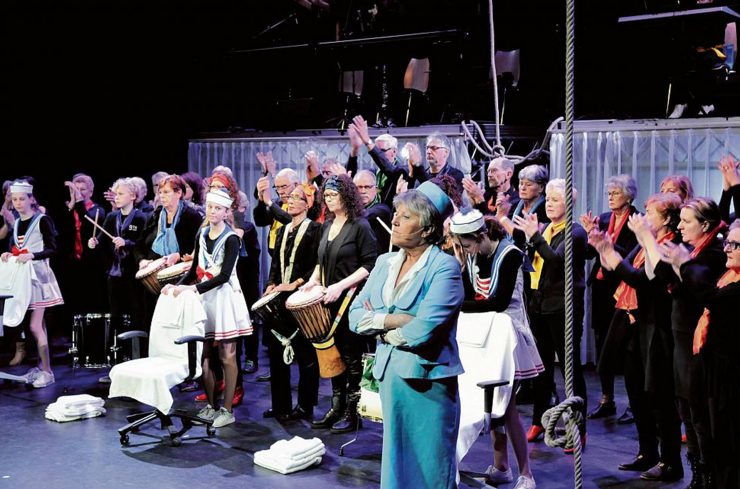 Groep acteurs en muzikanten op het podium in Theater Koningshof, ze spelen, dansen en zingen in een voorstelling voor en door mensen uit Maassluis