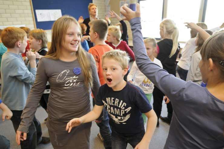 Leerlingen lopen dwars door elkaar in het lokaal tijdens een theaterles