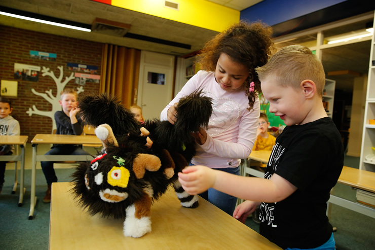 Twee leerlingen onderzoeken in de klas een pluche monster gemaakt van verschillende knuffeldieren die door elkaar heen gehusseld lijken