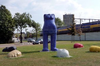 Kunstwerk door Chris Ripken van een staand blauw vrouwenlichaam zonder hoofd, om haar heen liggen hoofden in verschillende kleuren