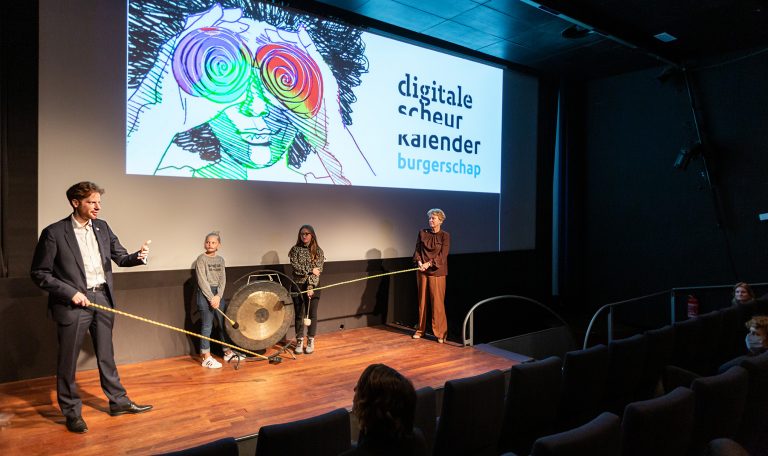 Gedeputeerden Floor Vermeulen en Willy de Zoete lanceerden samen met vmbo-leerlingen Sennah en Naomi op 27 oktober in het Filmhuis Den Haag de Digitale Scheurkalender Burgerschap door op een grote gong te slaan