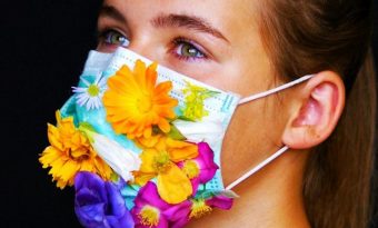 Vrouw met mondkapje dat versierd is met kleurige bloemen