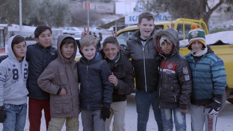 Twee kinderen uit Nederland tussen een groep kinderen die wonen in een vluchtelingenkamp op Lesbos - Beeld uit de film Hallo Salaam (2017)