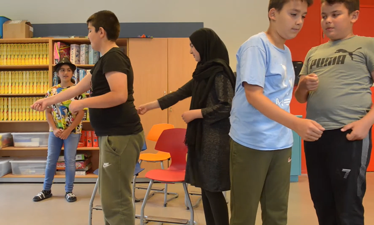 Leerkracht en kinderen doen theateropdrachten met hulp van de methodiek Taal en Theater