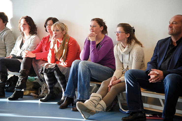 Leerkrachten zitten op een gymbank in het speellokaal tijdens workshop