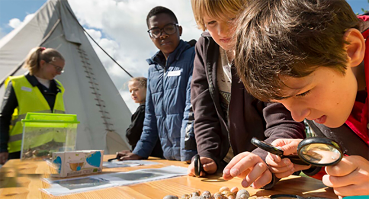 Kinderen bekijken schelpen met vergrootglas tijdens project Verwonder Om De Hoek in Holland Rijnland