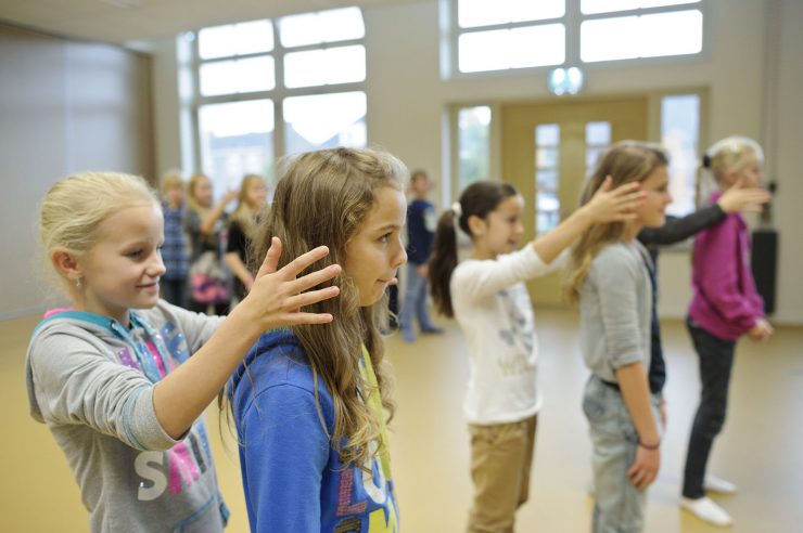 Basisschoolkinderen staan in rijen achter elkaar tijdens dansles in het speellokaal
