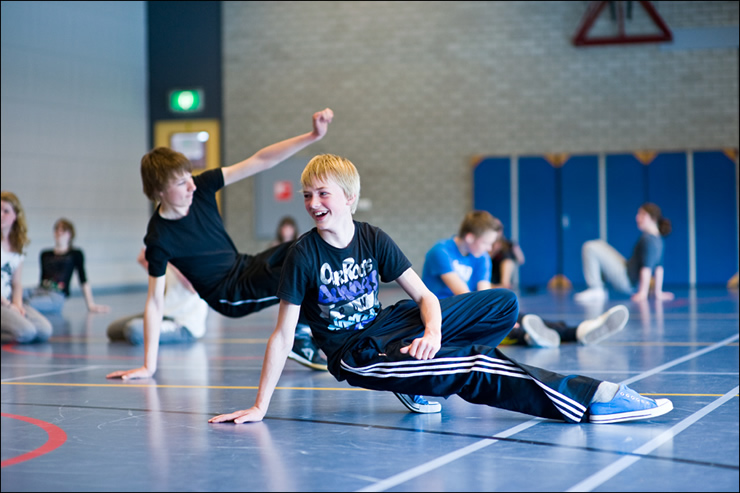 Tieners doen mee aan breakdanceworkshop in een gymzaal