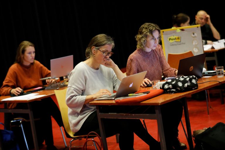 Deelnemers van Subsidiekamp Cultuurparticipatie zitten achter tafeltjes en werken achter laptop