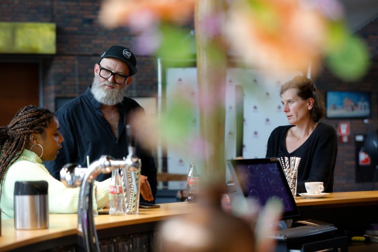 Drie deelnemers van Subsidiekamp Cultuurparticipatie praten na aan de bar in de foyer van het theater