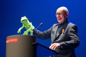 Theo Ham, oprichter en voormalig directeur Jeugdtheaterhuis, houdt een handpop van Kermit de Kikker omhoog