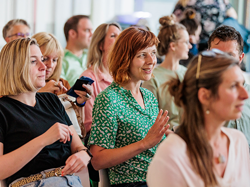 Docenten zitten in rijen en luisteren naar presentatie