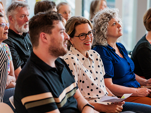 Docenten zitten in rijen en luisteren naar presentatie