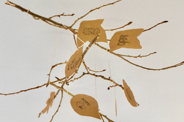 Een mobiel van takken en bladeren waarbij namen van een stamboom te zien zijn