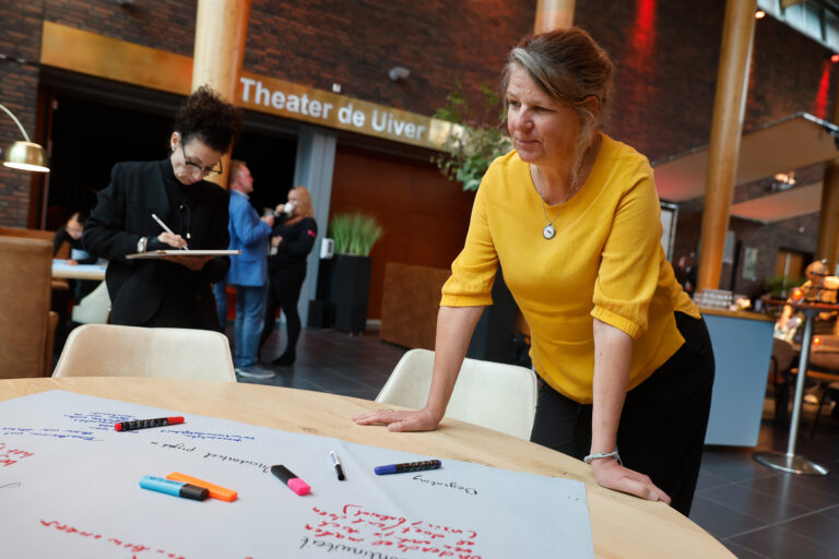 Een vrouw bekijkt aandachtig één van de posters tijdens de werksessie