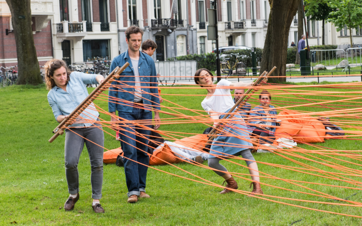 Mensen trekken aan touwen op een grasveld.