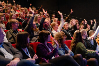 Personen in publiek steken hun hand op.