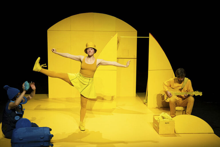 Twee acteurs in geheel geelgekleurd decor, ze dragen ook gele kleding. 1 acteur is in blauwe kleding.