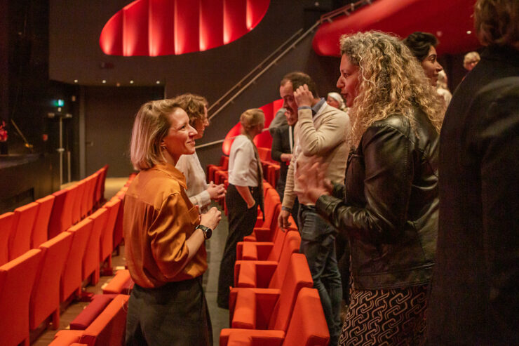 Netwerkbijeenkomst beleidsmakers erfgoed cultuur Publiek staat tussen stoelen in theaterzaal.