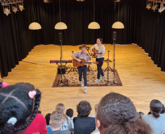 Meet Up 5 maart 2 mannen spelen gitaar voor publiek van kinderen