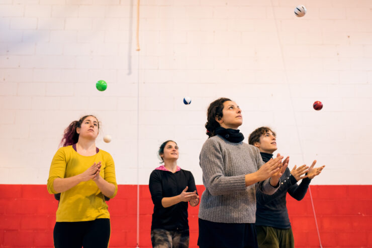 Group of women throwing up balls training skill and concentration standing in gym.
