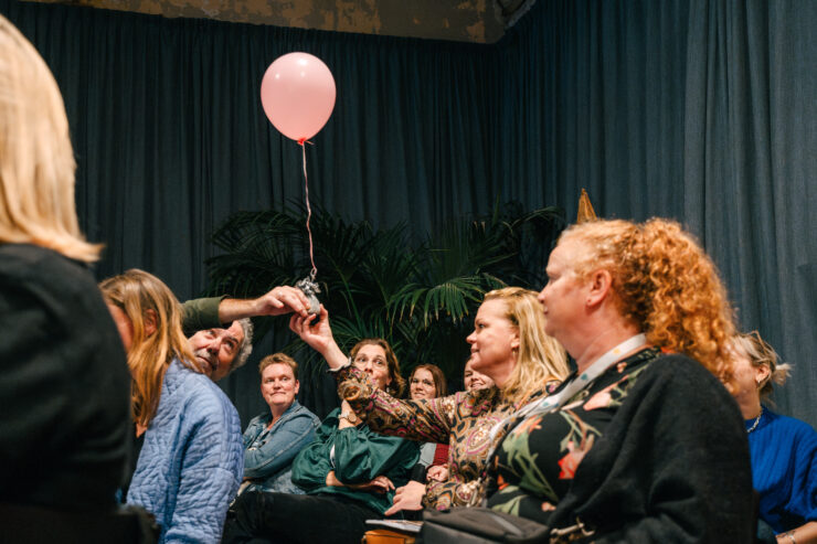 Een roze ballon wordt doorgegeven van persoon tot persoon tijdens een evenement,