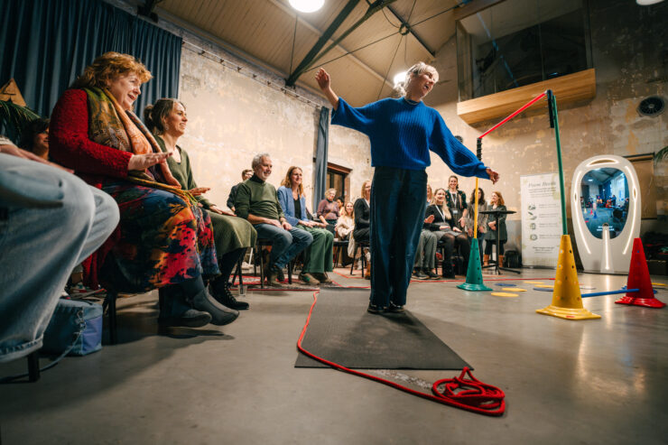 Jaarverslag 2024 vrouw in blauwe trui tussen publiek op stoelen