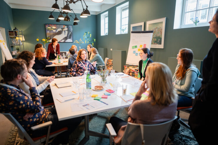Netwerkbijeenkomst cultuurverbinders personen aan een witte tafel die iets met elkaar bespreken