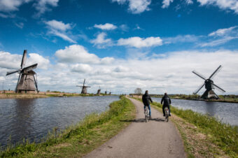 2 fietsers rijden door landschap met molens.