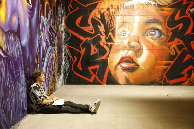 Man zit voor een graffiti wand te schrijven