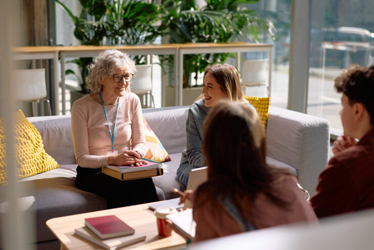 vrouw zit op een bank en praat met anderen.