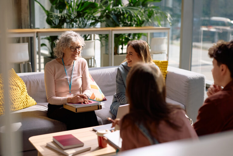 vrouw zit op een bank en praat met anderen.
