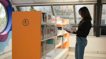 Deidre leest een boek in de bibliotheek.